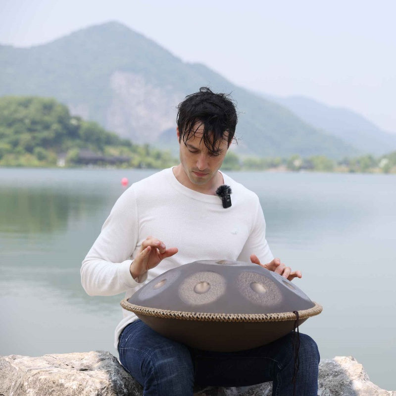 Artist playing handpan beside a peaceful river