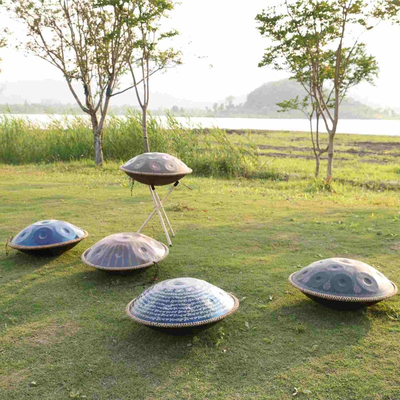 Handpans of different styles arranged on the grass, emphasizing variety.