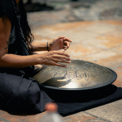 Close-up of a musician's hands skillfully striking the notes of a tongue drum in an indoor setting