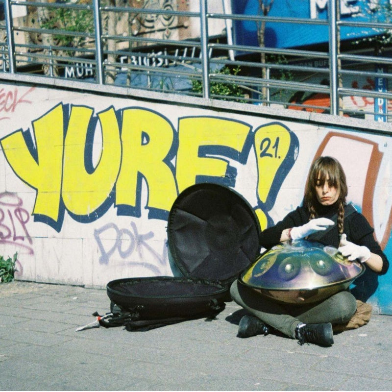 A serene moment of a female musician mastering her handpan in an outdoor environment