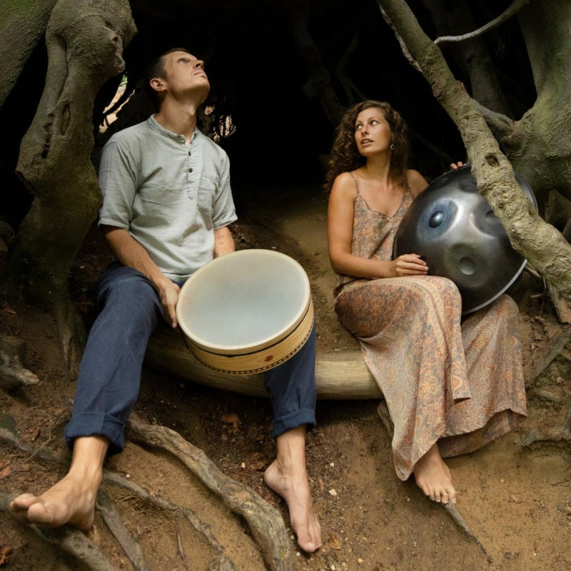 Two artists playing handpan in a forest ensemble