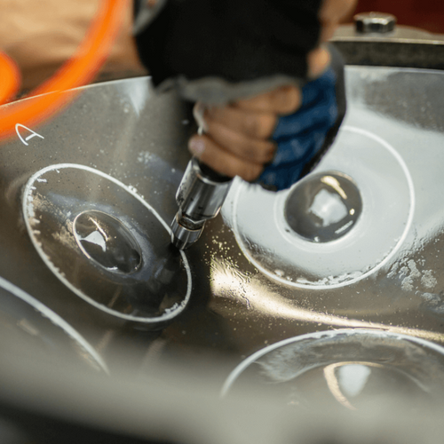 A handpan maker working with precision to create harmonious notes on the steel surface