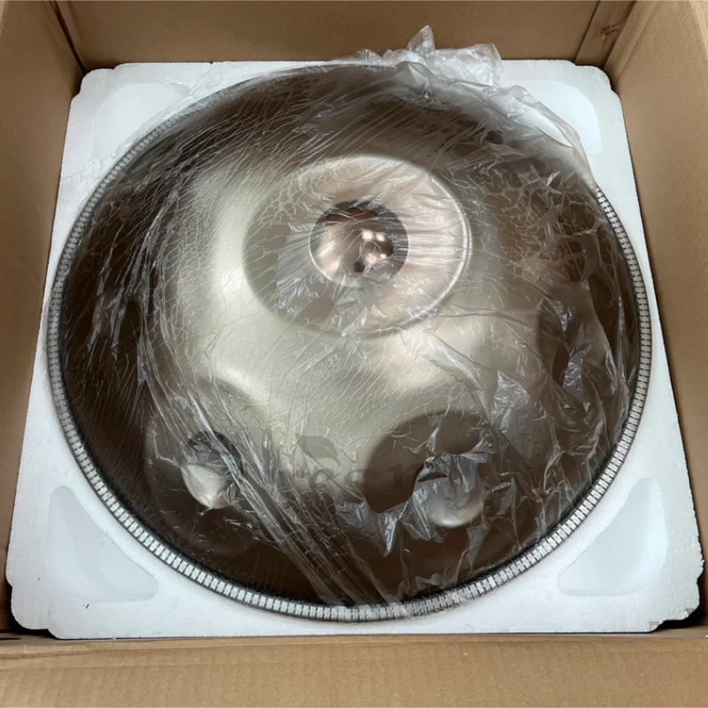 Close-up of a golden handpan packed in a cardboard box with cushioning material.