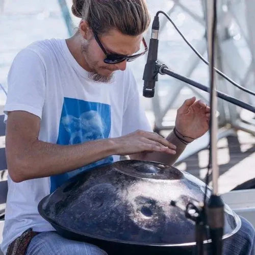 A passionate musician energetically playing a handpan in an outdoor setting