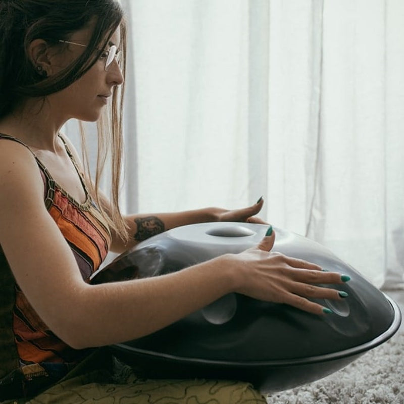 The woman playing handpan in a cozy room