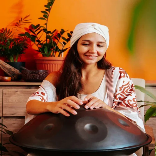 A talented female musician playing a handpan indoors, creating soulful melodies in a cozy setting