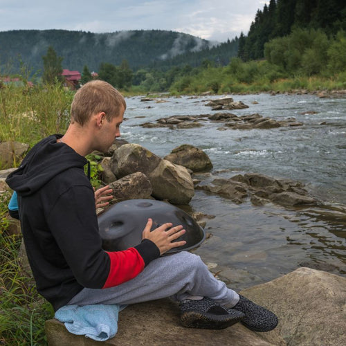 Handpan performance by a musician beside a flowing creek