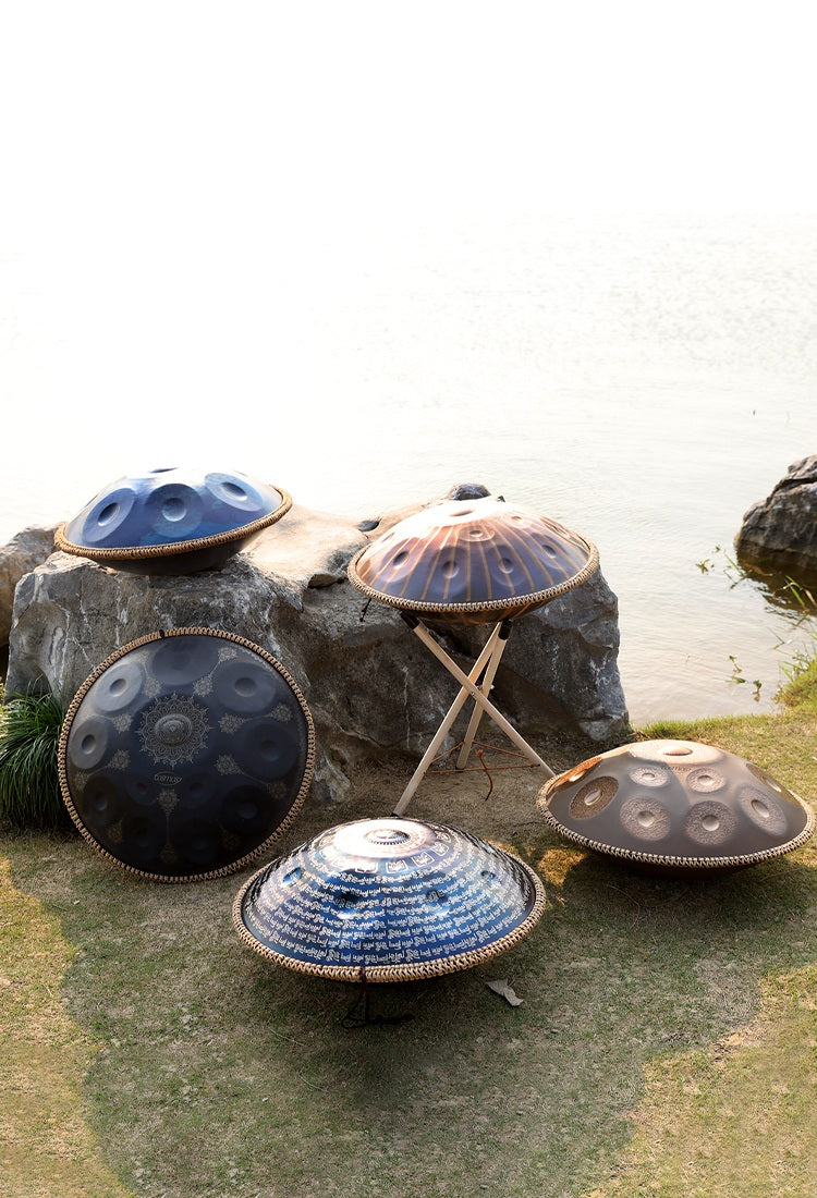 Handpans of various designs on display near a scenic lake